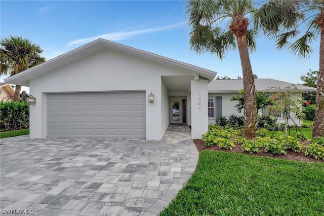 ranch-style home featuring decorative driveway, an attached garage, and stucco siding