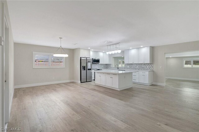 kitchen featuring stainless steel appliances, white cabinets, backsplash, light hardwood / wood-style floors, and a center island