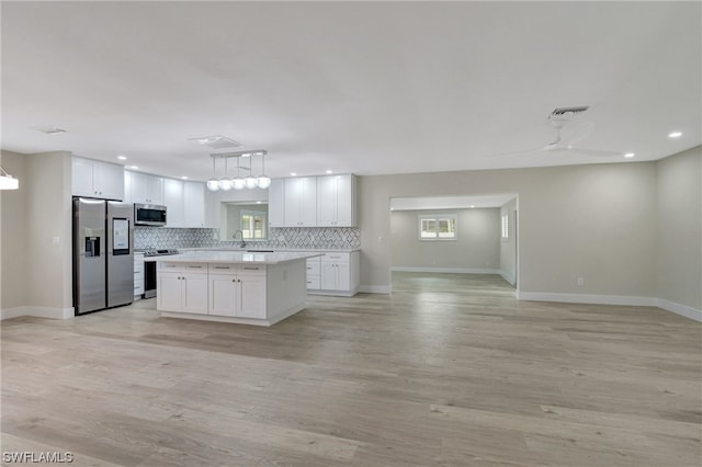 kitchen featuring white cabinets, stainless steel appliances, light hardwood / wood-style floors, and a kitchen island