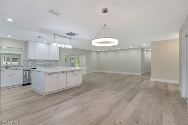 kitchen featuring stainless steel dishwasher, tasteful backsplash, pendant lighting, white cabinets, and light hardwood / wood-style flooring