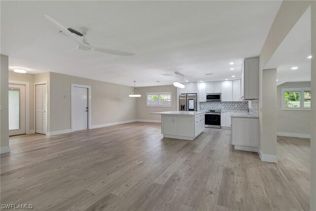 kitchen featuring appliances with stainless steel finishes, white cabinetry, a center island, and light wood-type flooring