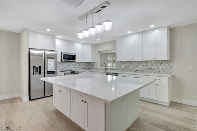 kitchen with tasteful backsplash, a center island, light hardwood / wood-style floors, appliances with stainless steel finishes, and decorative light fixtures