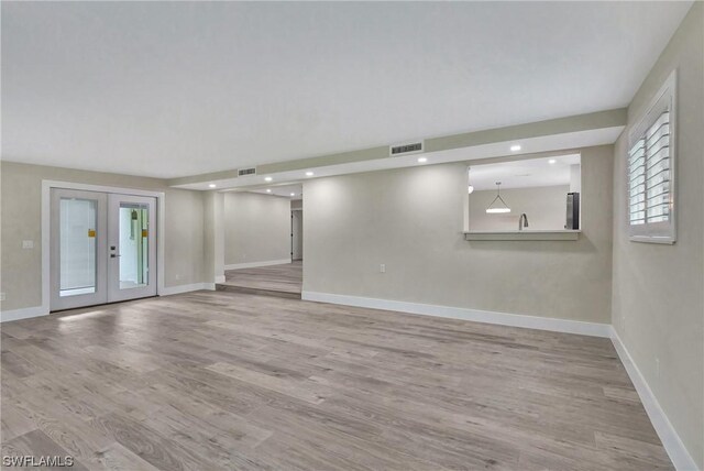 unfurnished living room with french doors and light wood-type flooring