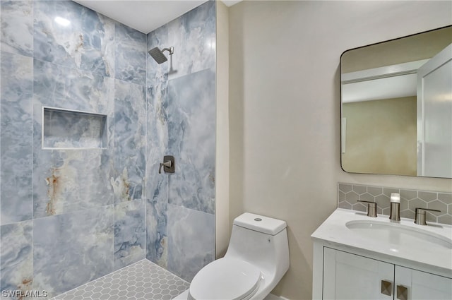 bathroom featuring vanity, tiled shower, tasteful backsplash, and toilet