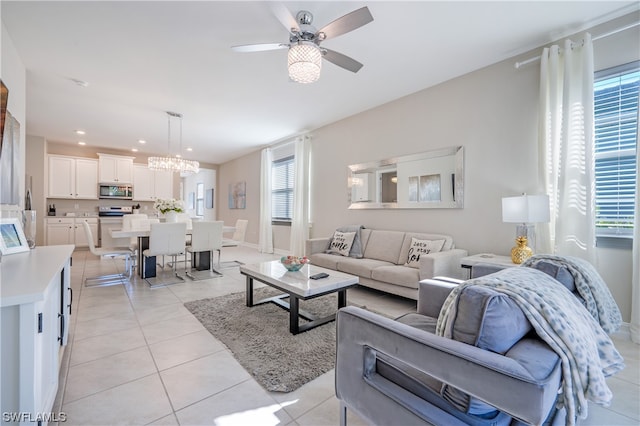 living room with light tile patterned flooring, ceiling fan with notable chandelier, and plenty of natural light