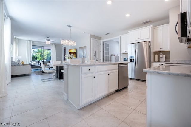 kitchen featuring hanging light fixtures, sink, appliances with stainless steel finishes, light tile patterned floors, and a kitchen island with sink