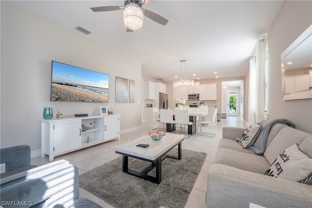 tiled living room with ceiling fan with notable chandelier