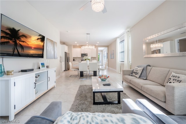 tiled living room with ceiling fan with notable chandelier