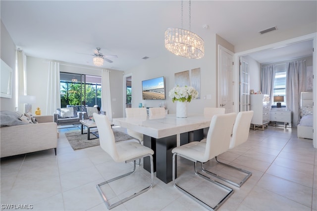 dining space featuring light tile patterned flooring and ceiling fan with notable chandelier