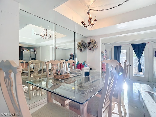 dining space featuring an inviting chandelier, a tray ceiling, and tile patterned flooring