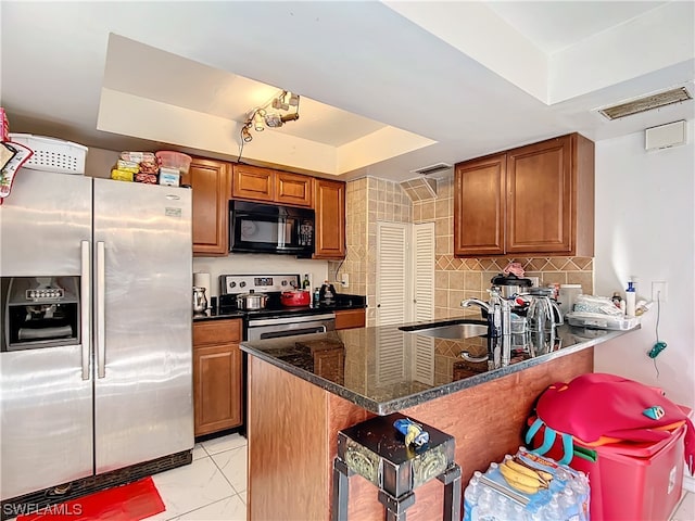 kitchen with sink, kitchen peninsula, stainless steel appliances, dark stone counters, and decorative backsplash