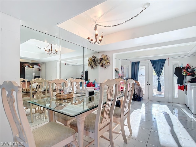 tiled dining space with a raised ceiling, an inviting chandelier, and french doors