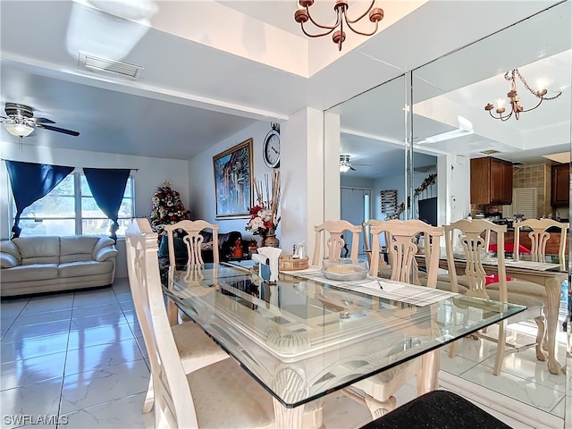 dining area featuring ceiling fan with notable chandelier and a raised ceiling