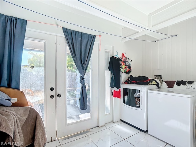 clothes washing area featuring wood walls and washer and clothes dryer