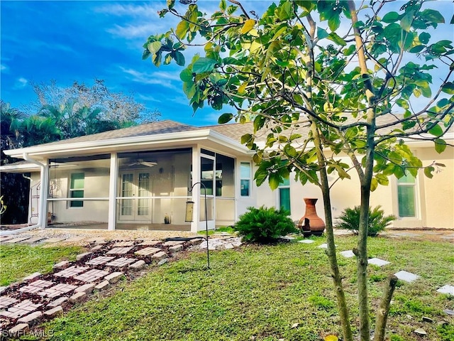 rear view of property featuring a sunroom, a yard, and ceiling fan