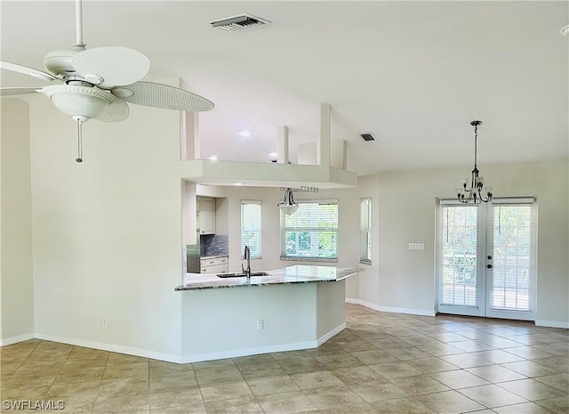 kitchen with vaulted ceiling, a wealth of natural light, decorative light fixtures, sink, and light stone countertops