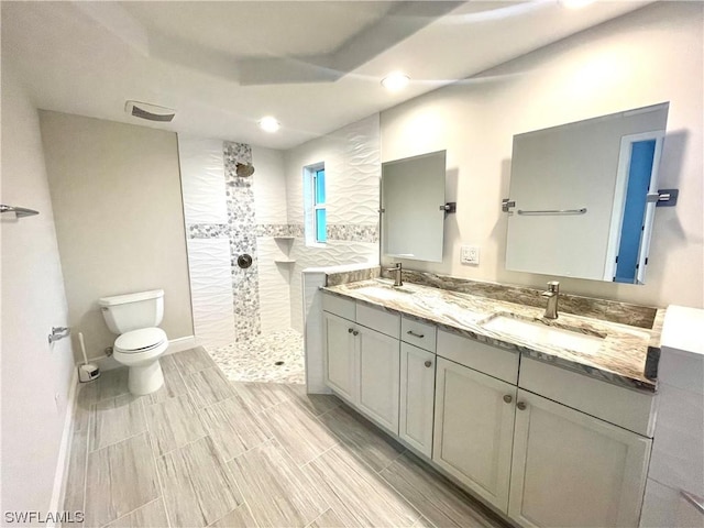 bathroom with a tile shower, vanity, and toilet