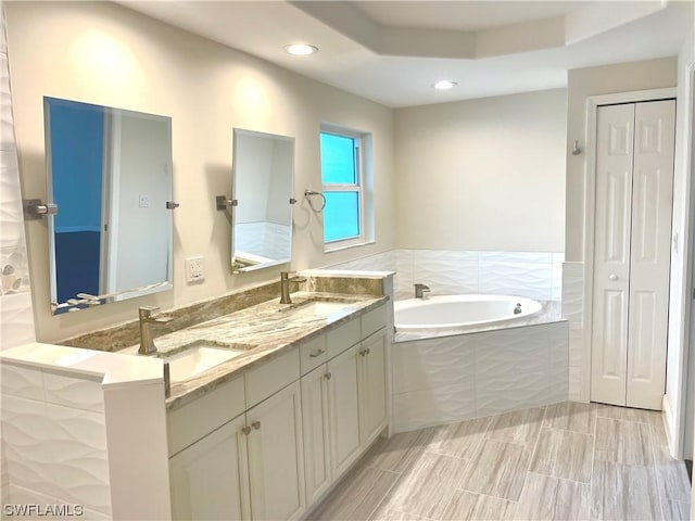 bathroom featuring a relaxing tiled tub and vanity