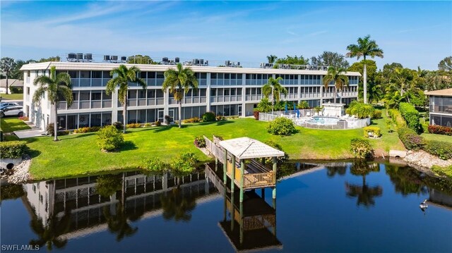 exterior space featuring a water view, a community pool, and a lawn