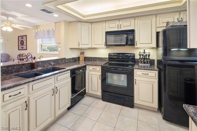 kitchen featuring black appliances, ceiling fan, a tray ceiling, cream cabinetry, and crown molding