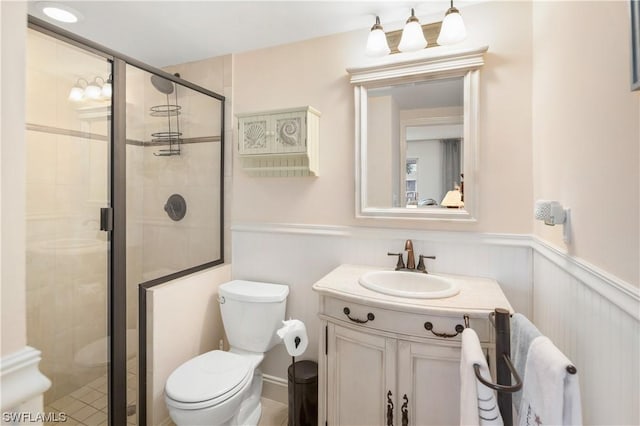 bathroom featuring vanity, toilet, and a shower with door