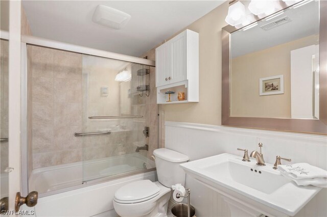 full bathroom with toilet, shower / bath combination with glass door, and sink