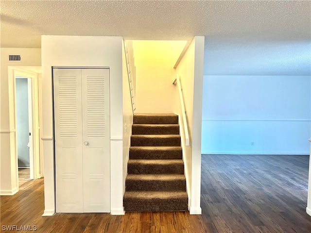 stairs with a textured ceiling and hardwood / wood-style floors