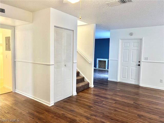 interior space with a textured ceiling and dark hardwood / wood-style flooring