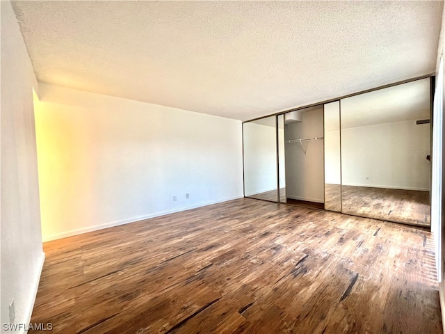 unfurnished bedroom with a textured ceiling, wood-type flooring, and a closet