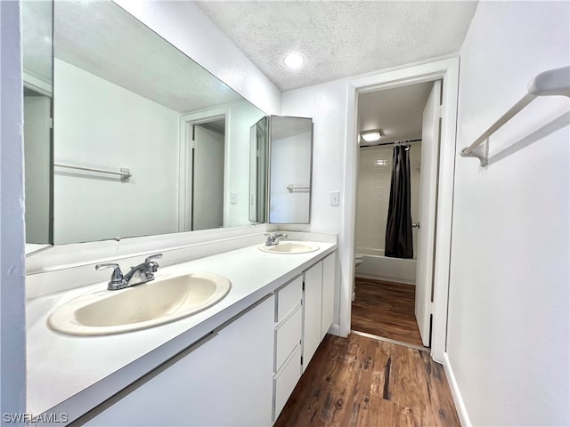 bathroom featuring wood-type flooring, a textured ceiling, a shower with shower curtain, vanity, and toilet