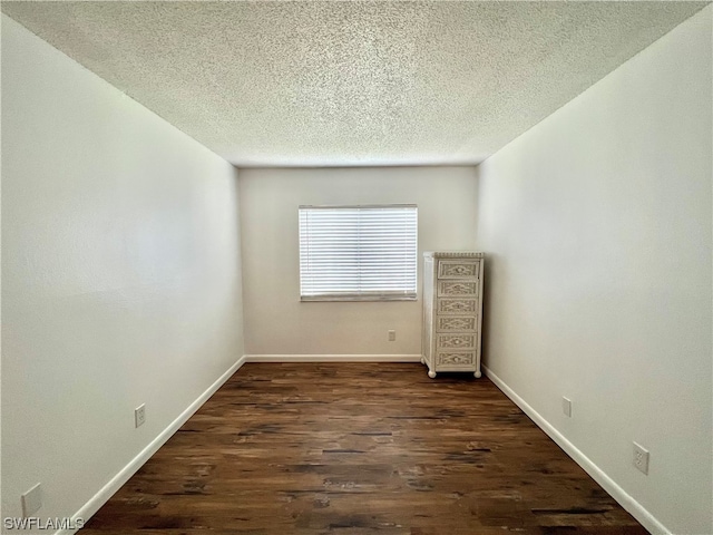 spare room featuring a textured ceiling and dark hardwood / wood-style floors