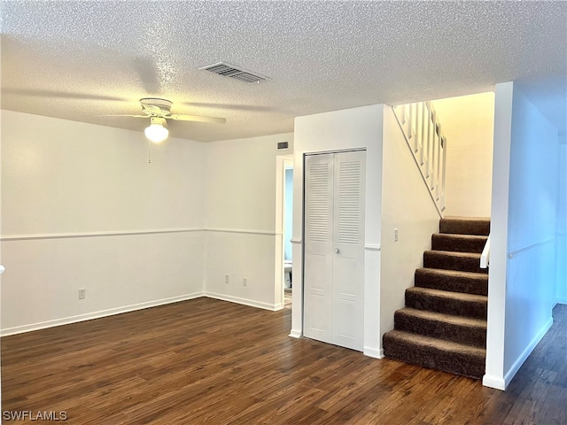 basement featuring ceiling fan, a textured ceiling, and dark hardwood / wood-style floors