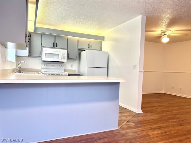 kitchen featuring white appliances, kitchen peninsula, and a textured ceiling