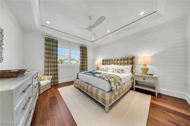 bedroom featuring a raised ceiling, dark hardwood / wood-style flooring, and ceiling fan