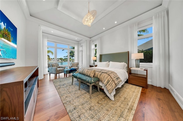 bedroom featuring dark wood-type flooring, a raised ceiling, and a chandelier