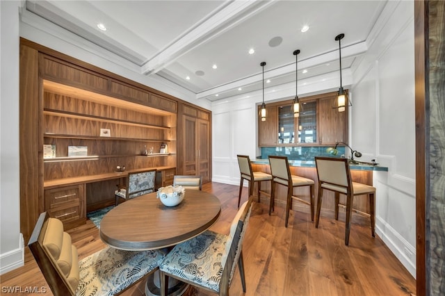 dining room with hardwood / wood-style flooring, beamed ceiling, and built in features