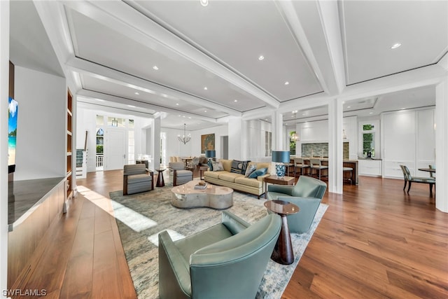 living room featuring beamed ceiling, a notable chandelier, and hardwood / wood-style floors