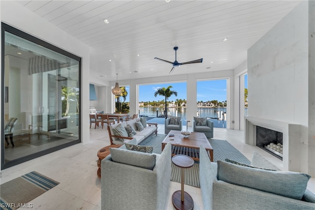 living room with ceiling fan, a water view, and plenty of natural light