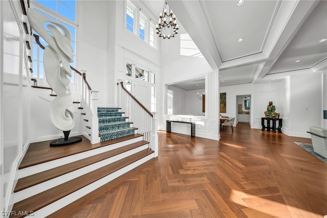 foyer with parquet floors, an inviting chandelier, and a high ceiling