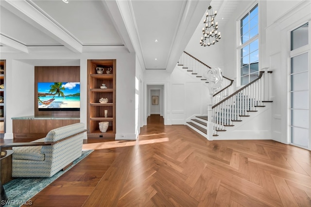 foyer with beamed ceiling, a notable chandelier, crown molding, and parquet floors