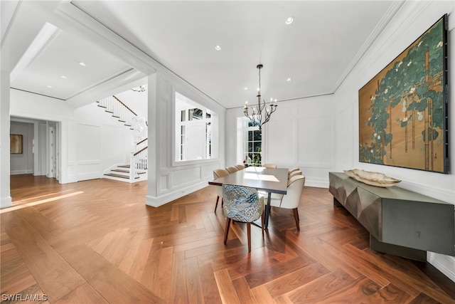 dining space with an inviting chandelier, crown molding, and parquet flooring