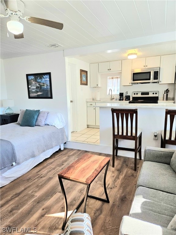 living room featuring ceiling fan, sink, and wood-type flooring