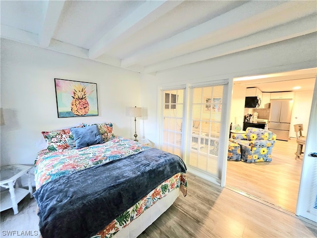 bedroom featuring beam ceiling, light wood-type flooring, and white fridge