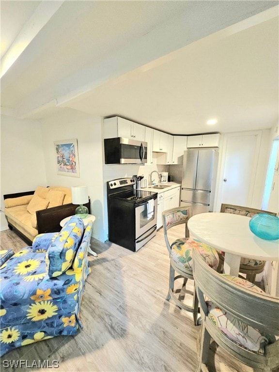 kitchen with white cabinetry, sink, stainless steel appliances, and light hardwood / wood-style flooring