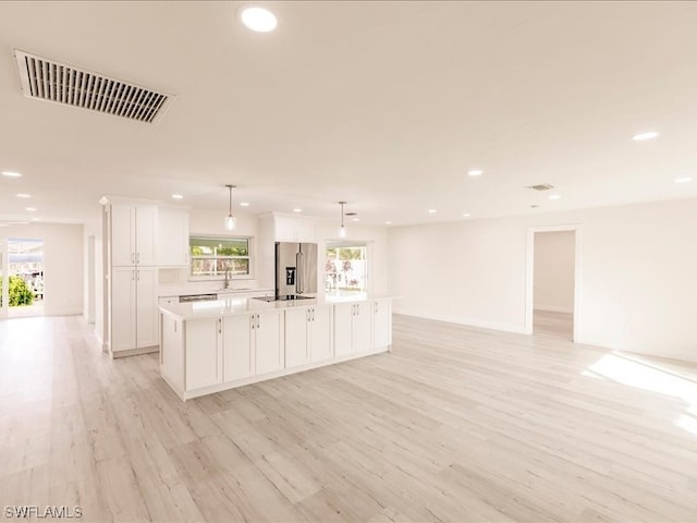 kitchen featuring decorative light fixtures, a center island, stainless steel fridge with ice dispenser, white cabinetry, and light wood-type flooring