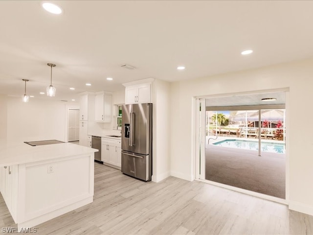 kitchen with light hardwood / wood-style floors, decorative light fixtures, appliances with stainless steel finishes, white cabinets, and sink