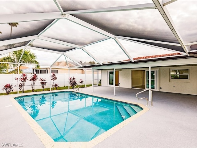 view of swimming pool featuring glass enclosure and a patio