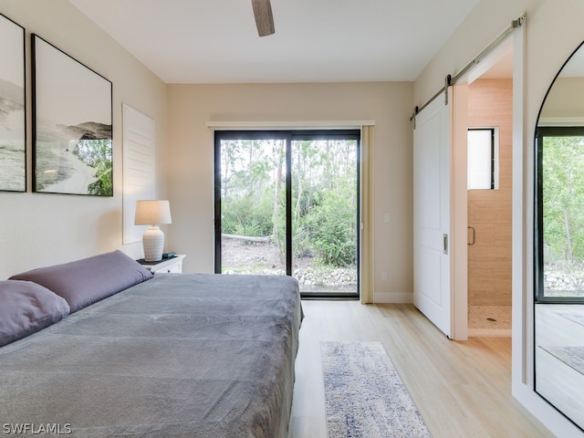 unfurnished bedroom featuring a barn door, ceiling fan, multiple windows, and light wood-type flooring