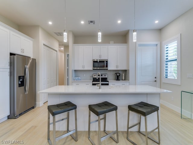 kitchen featuring appliances with stainless steel finishes, pendant lighting, and a kitchen island with sink