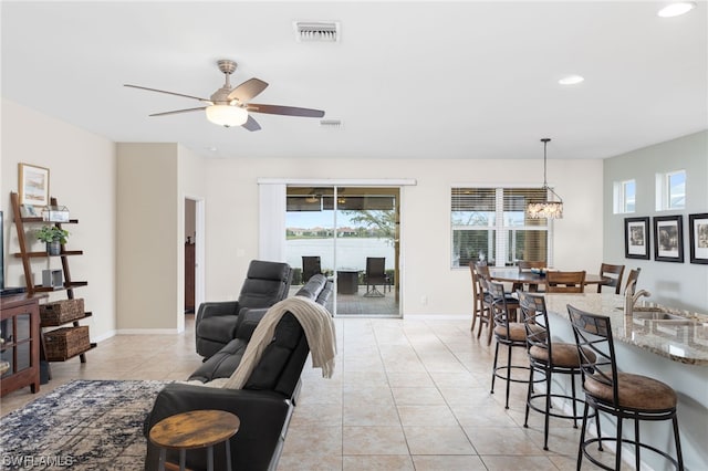 tiled living room featuring sink and ceiling fan with notable chandelier